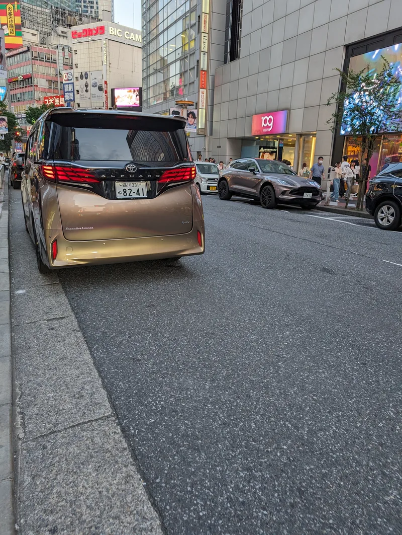 Rear view of a gold Toyota Alphard minivan parked on a street in Shibuya, Tokyo, Japan.