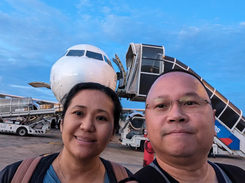 Couple taking a selfie on the tarmac in front of a Philippine Airlines airplane at Manila airport