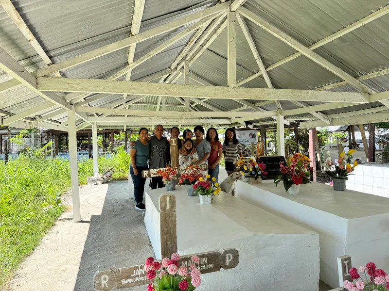 Family members posing for a group photo at a cemetery in Palawan, Philippines