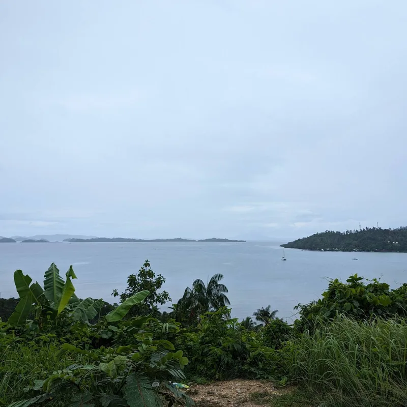 Panoramic view of a bay with small islands and lush green hills under a cloudy overcast sky on the road between Sabang and Puerto Princesa, Palawan, Philippines