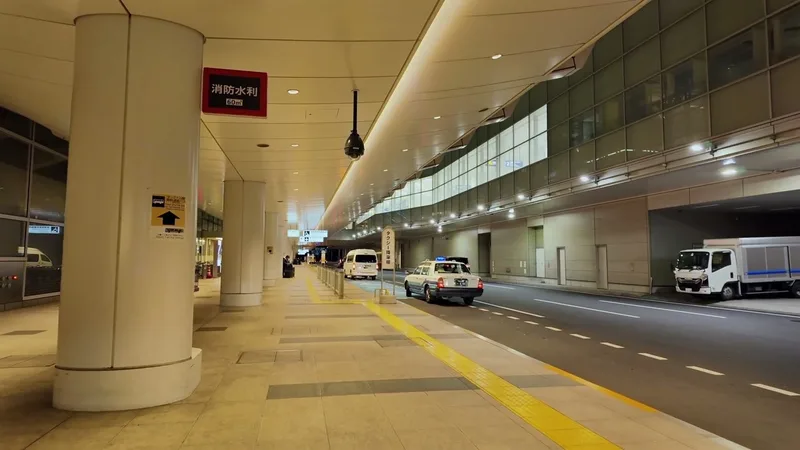 Quiet outdoor pickup area at night at Haneda Airport Terminal 3, Tokyo, Japan with taxi and covered walkway