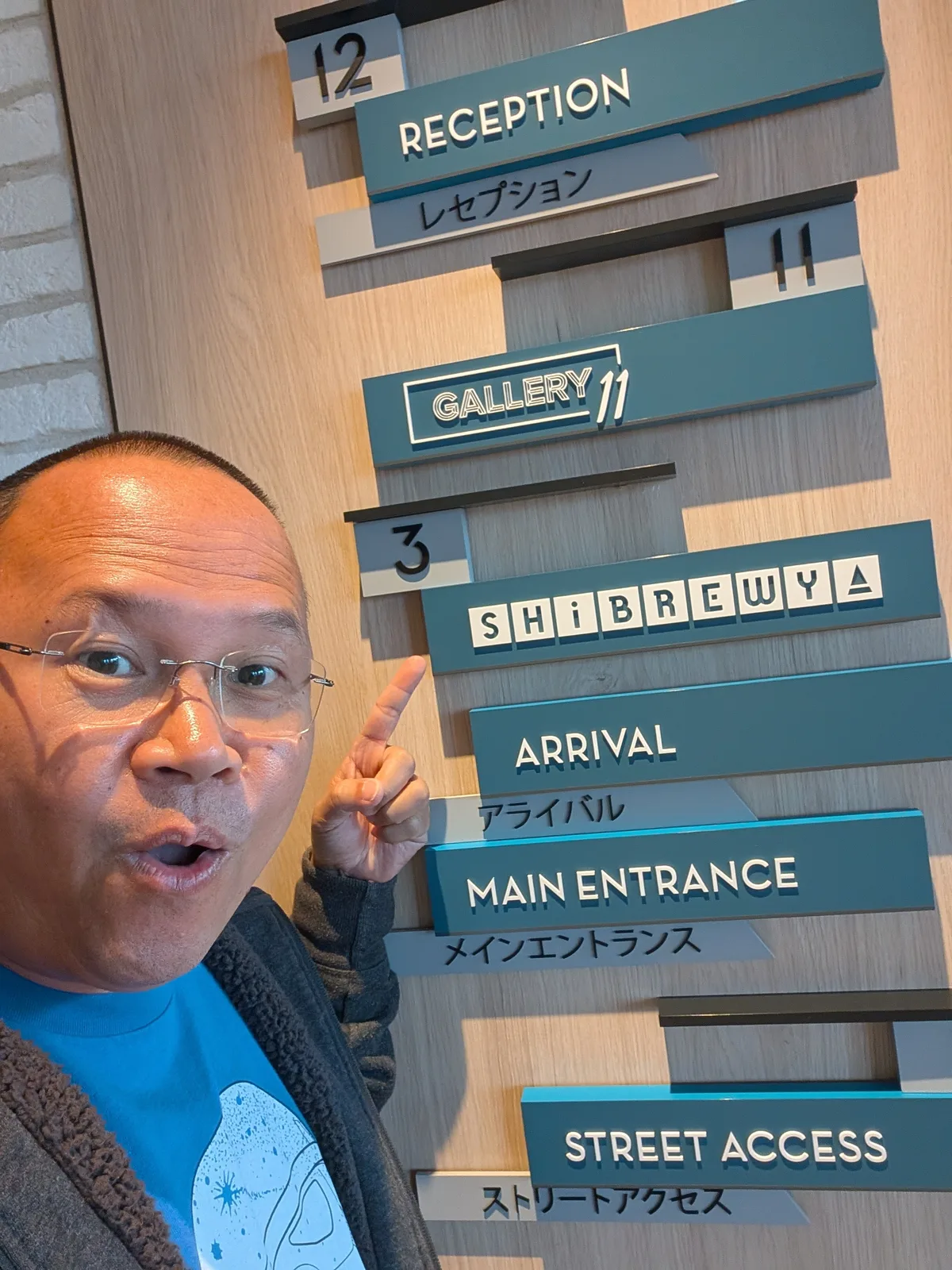 Man pointing excitedly at directional signs including Arrival and Main Entrance at Haneda Airport, Tokyo, Japan