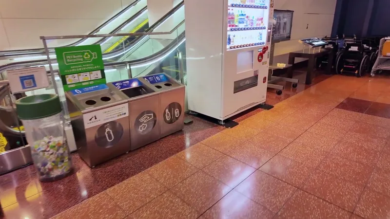 Japanese vending machine with recycling bins beside an escalator at Haneda Airport, Tokyo, Japan
