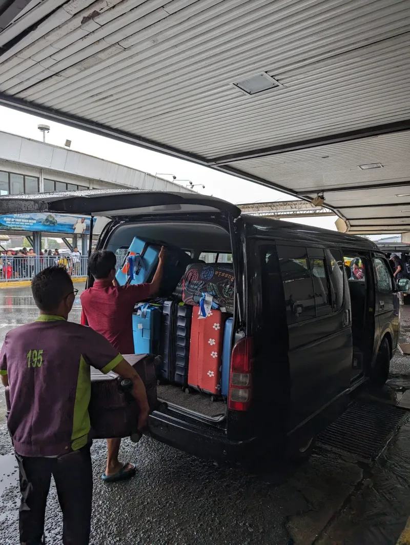 Airport porters loading suitcases into a van in Manila