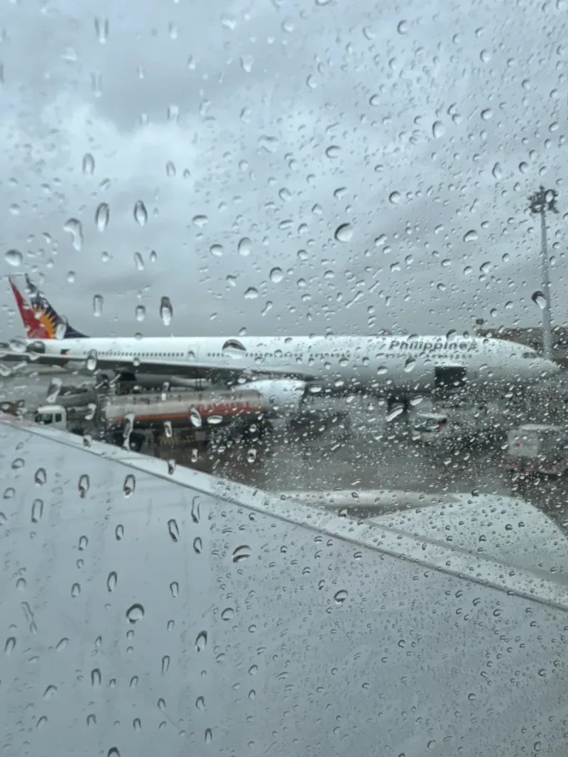 Philippine Airlines plane seen through rain-streaked window
