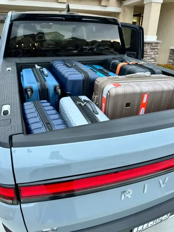 Rivian truck bed packed with suitcases for travel