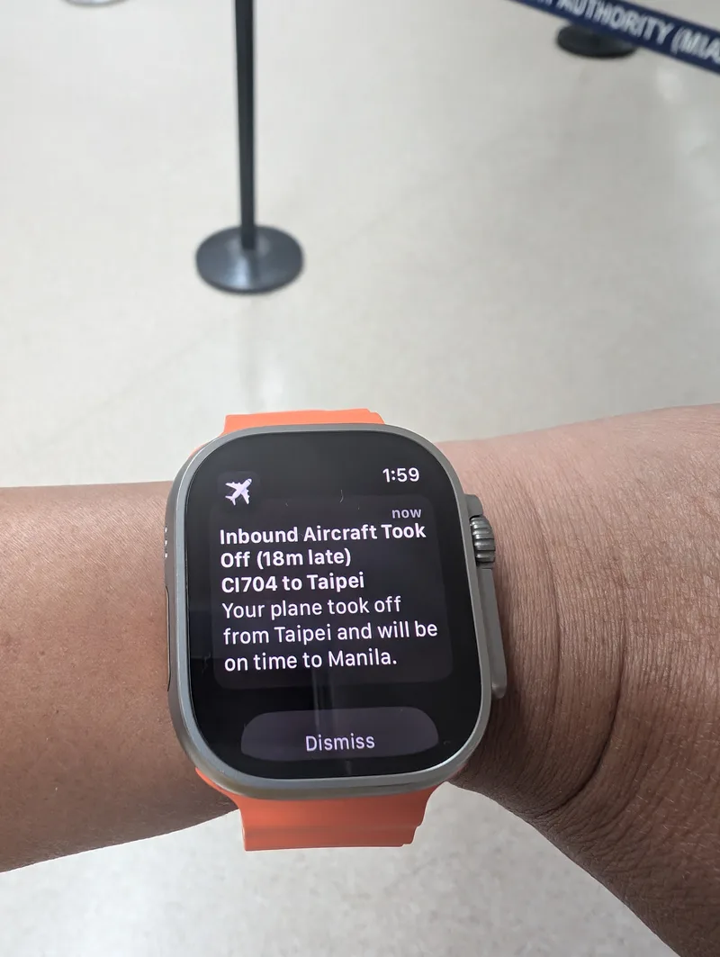 Tracking the inbound connection — Manila Airport, Philippines Apple Watch Ultra displaying a flight tracking notification for China Airlines CI704 from Taipei, showing an 18-minute late departure but on-time arrival at Manila, Philippines.