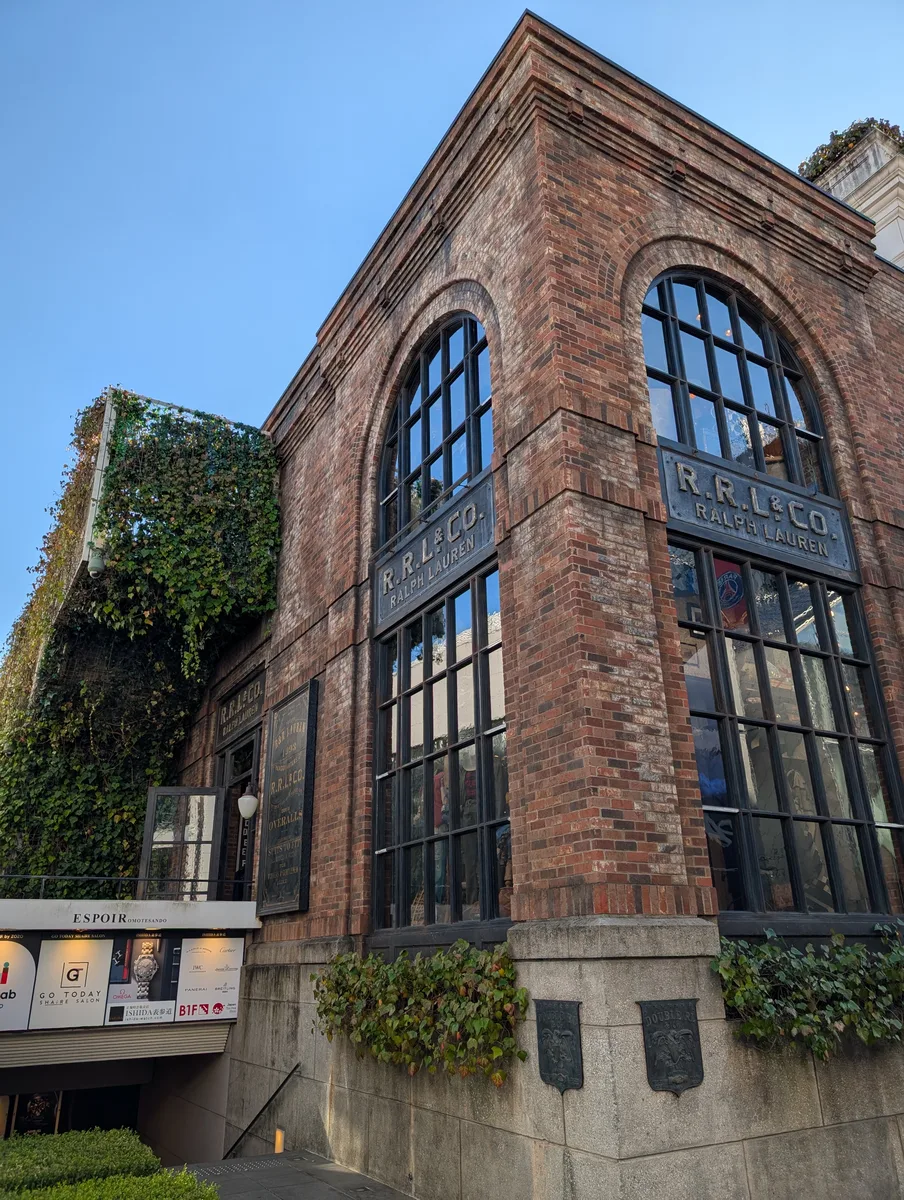 Ivy-covered brick R.R.L. & Co. Ralph Lauren building with tall arched windows under a clear blue sky in Harajuku, Tokyo, Japan