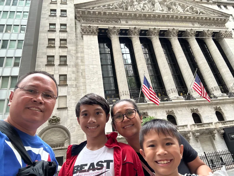 Family selfie in front of New York Stock Exchange with American flags