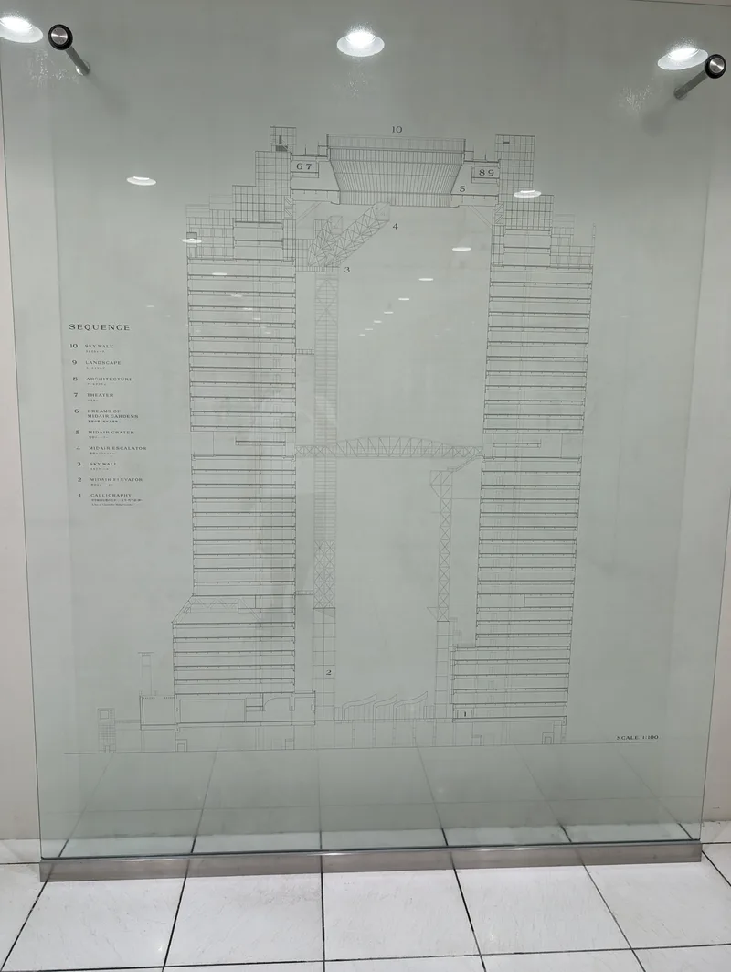 Man taking selfie at Umeda Sky Building interior with building blueprint display in Osaka, Japan.