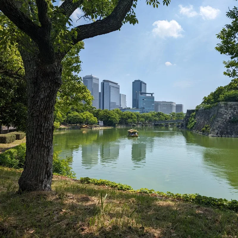 Osaka Castle moat with boat and city skyline visible in the distance, Osaka, Japan.