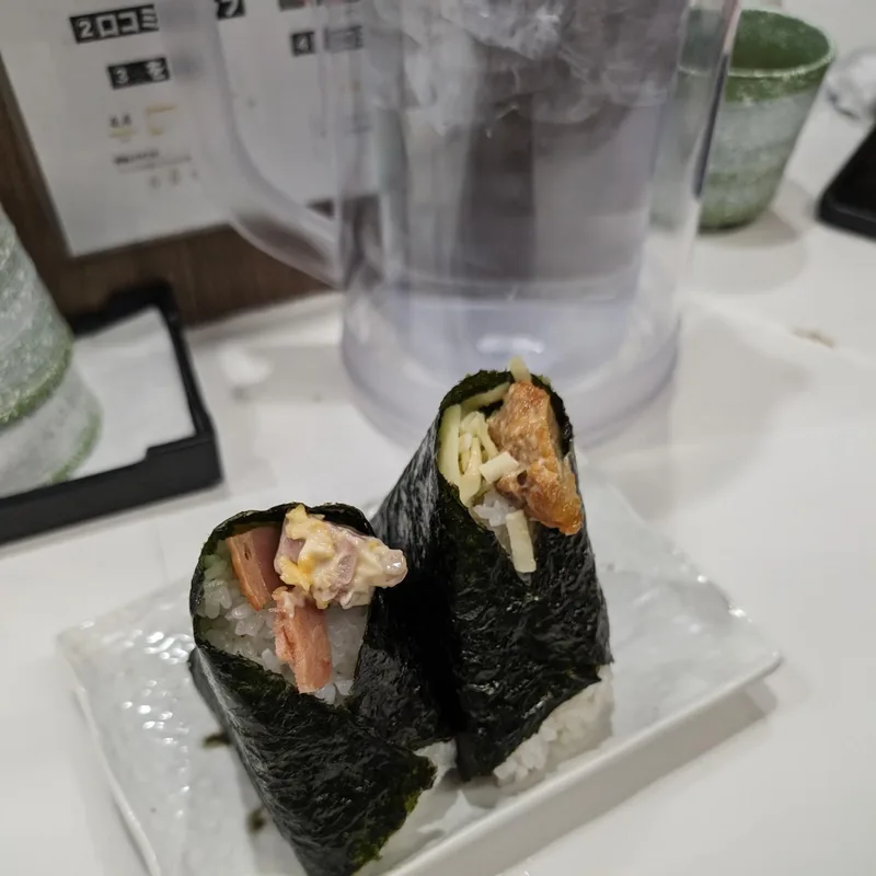 Two onigiri wrapped in nori seaweed on a white plate at Onigiri Gorichan in Osaka, Japan.