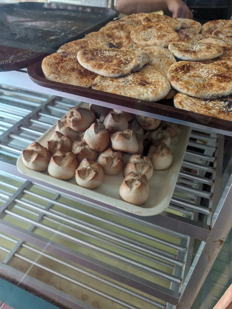 Stacked trays of various pastries including sesame seed cookies and small buns inside Modern Bakery in Roxas Palawan