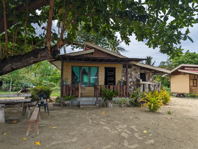 The cottage we stayed in — faces the beach Small yellow cottage with stone facade and wooden porch surrounded by tropical plants at Henalric resort in Caramay, Roxas, Palawan