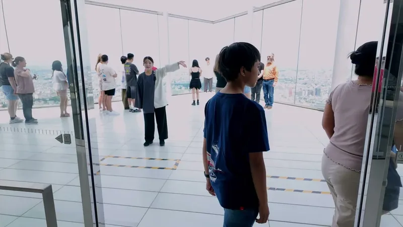 Inside the Shibuya Sky indoor observation floor, Shibuya, Tokyo, Japan People inside the Shibuya Sky observation deck looking at the Tokyo, Japan city skyline through glass windows, a young boy in a blue shirt in the foreground.
