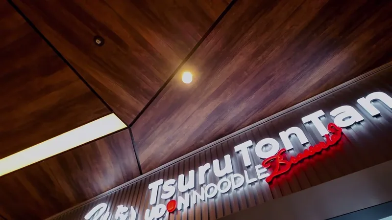 Tsuru Ton Tan Udon Noodle Brasserie, 13th floor of Shibuya Sky, Shibuya, Tokyo, Japan Tsuru Ton Tan Udon Noodle Brasserie neon sign with red lettering and warm wooden ceiling at Shibuya Sky, Shibuya, Tokyo, Japan.