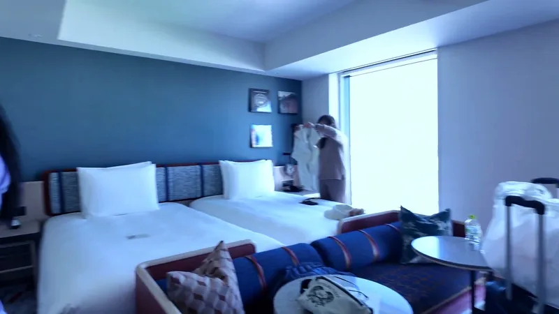 Modern hotel room with two beds, blue accent wall, and natural light at Hotel Indigo Shibuya on the 15th floor in Tokyo, Japan