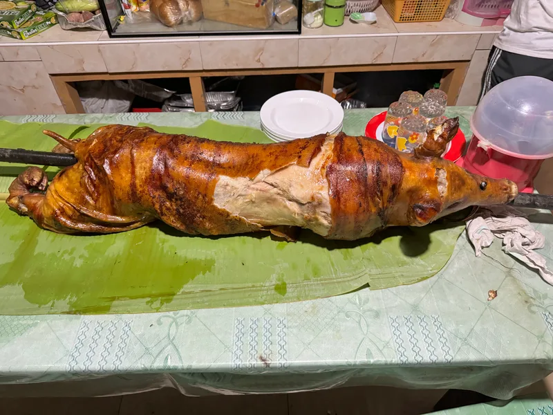 Whole roasted pig lechon laid out on banana leaves ready to be served at a Filipino family gathering in Palawan