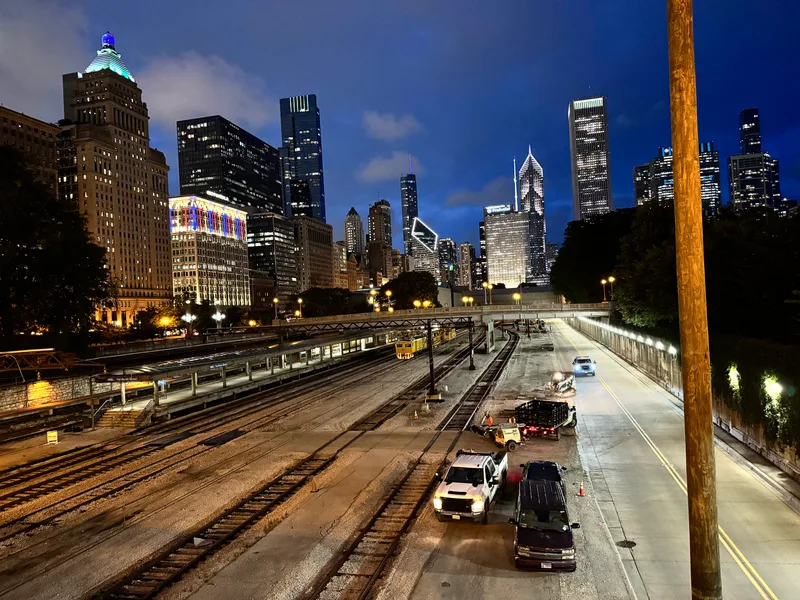 Chicago, Illinois skyline illuminated at night, viewed from elevated train tracks with cars below