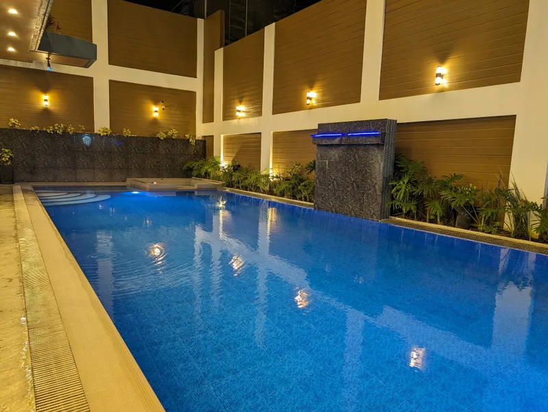 Illuminated hotel swimming pool at Avery Ridge Resort in Pansol, Laguna at night with blue water, waterfall, and warm wall lights.